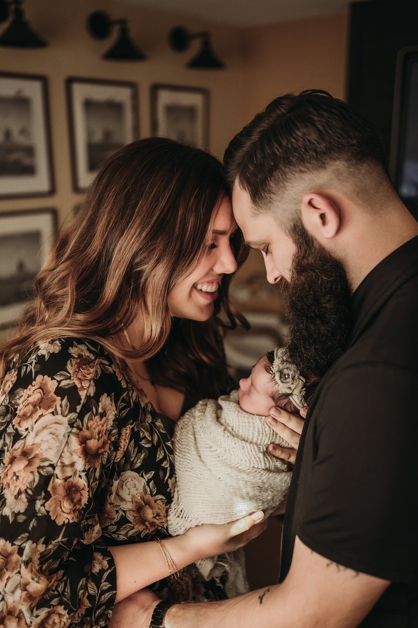 Intimate family moment in warm lighting with floral dress and black shirt against framed wall art.