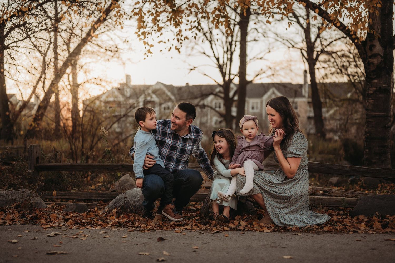 Family sitting together on fall path during golden hour sunset.