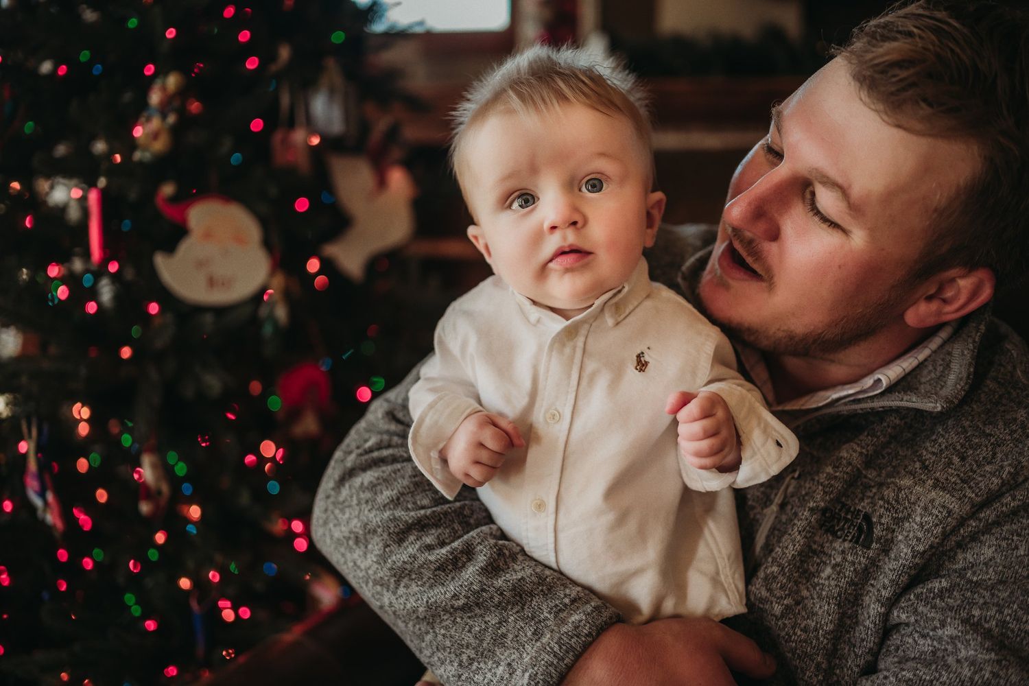 Tender holiday moment captured by decorated Christmas tree with red ornaments.