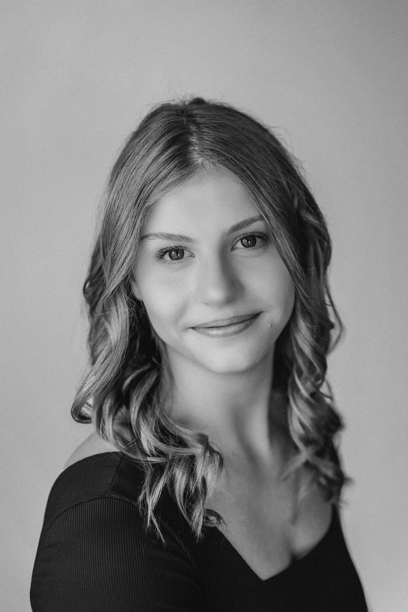 Black and white headshot portrait with soft lighting and gentle smile.