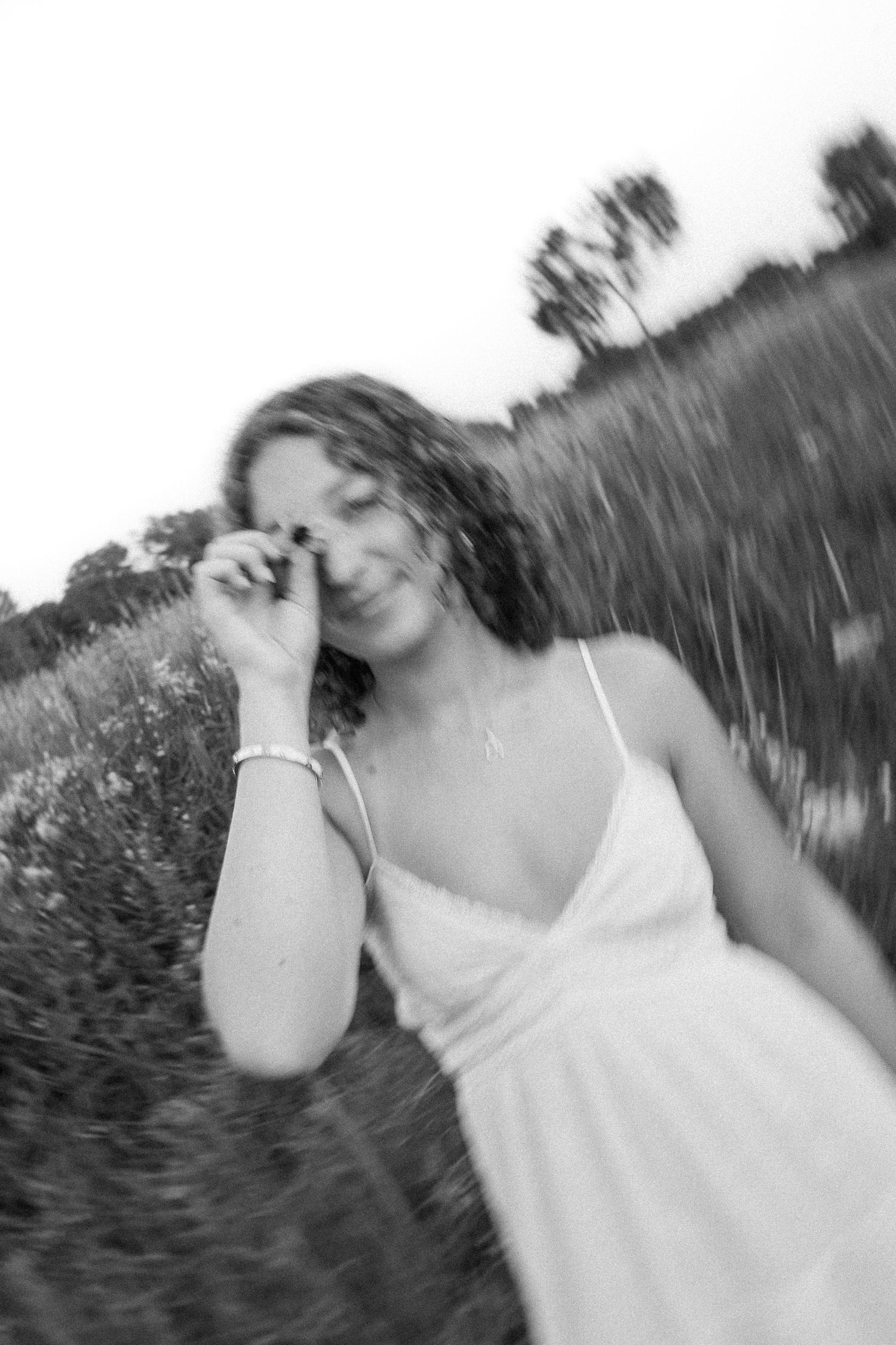 A black and white motion-blurred portrait capturing a carefree moment in a field.