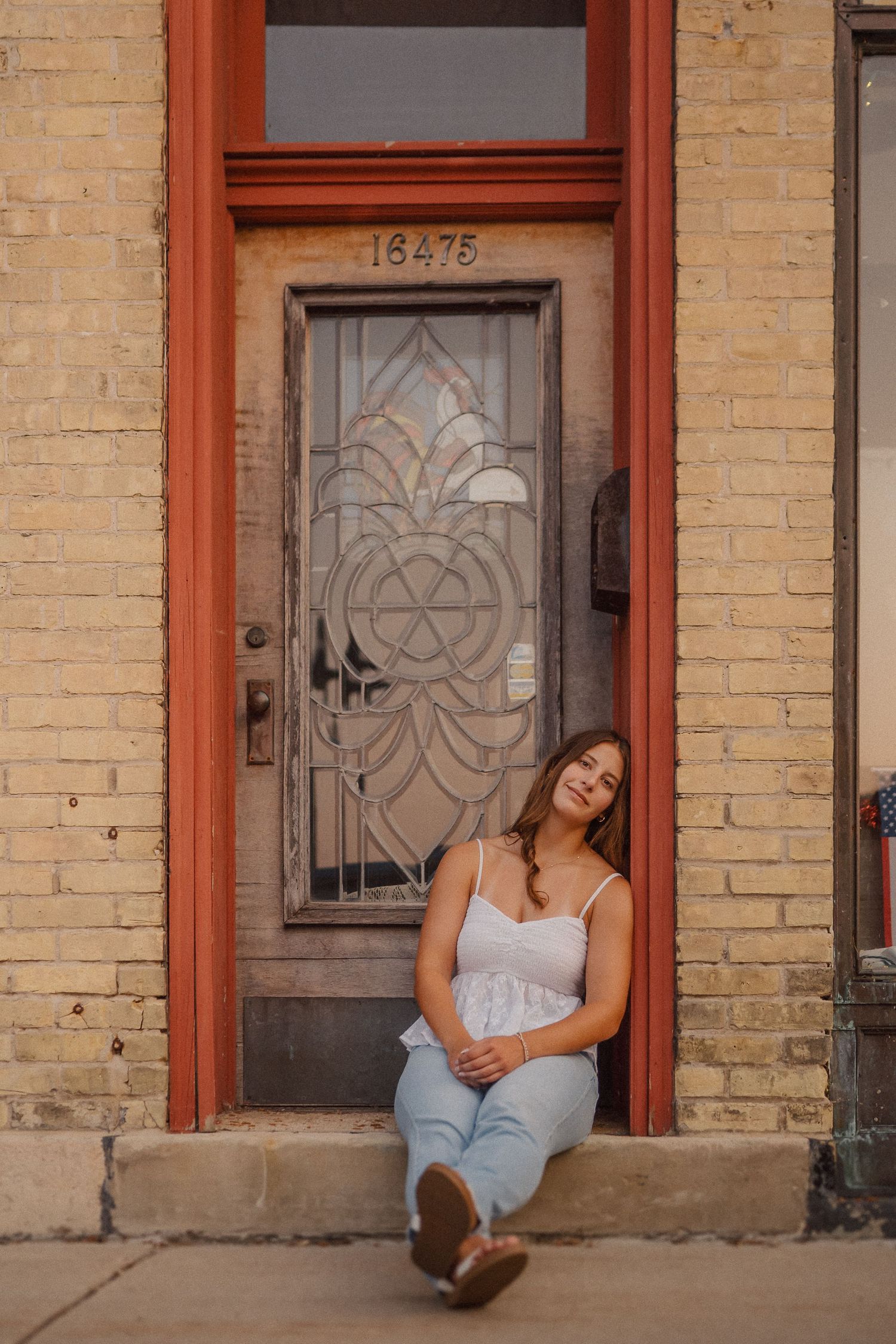 Casual portrait series against vintage brick storefront with decorative red-trimmed doorways.
