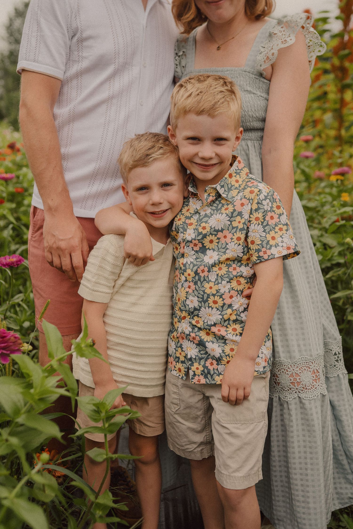 Casual family portrait showing legs and torso in coordinated summer outfits of floral dresses and khaki shorts.