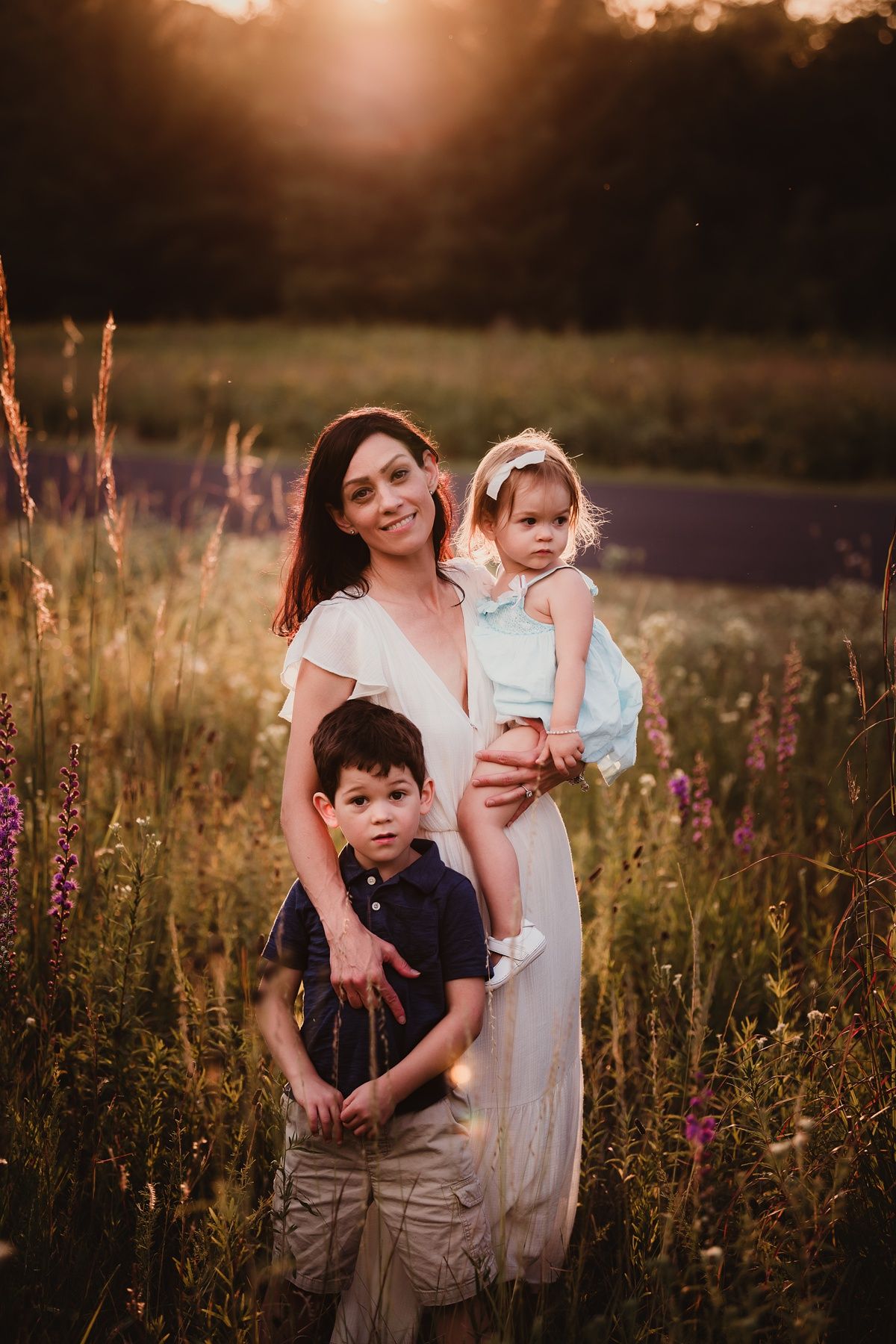 Beautiful family portrait in a wild meadow during golden hour sunset.