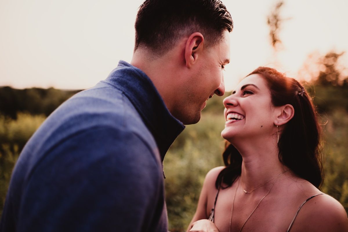 Romantic couple sharing an intimate moment at sunset in a field.