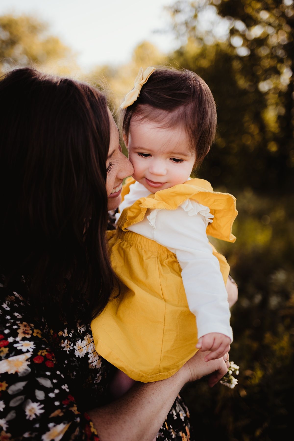 Warm sunset portrait of adult and baby sharing a close moment outdoors.