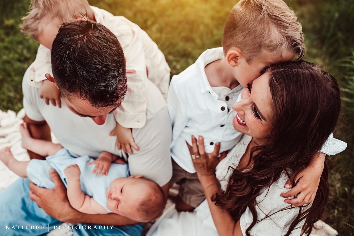 Candid family moment captured on white blanket during outdoor photo session.