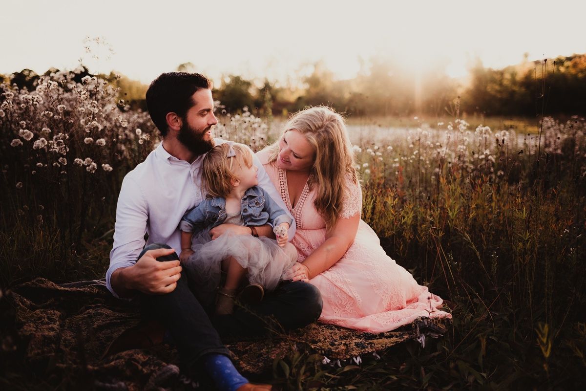 Intimate family moment captured in a golden-lit wildflower field at dusk.
