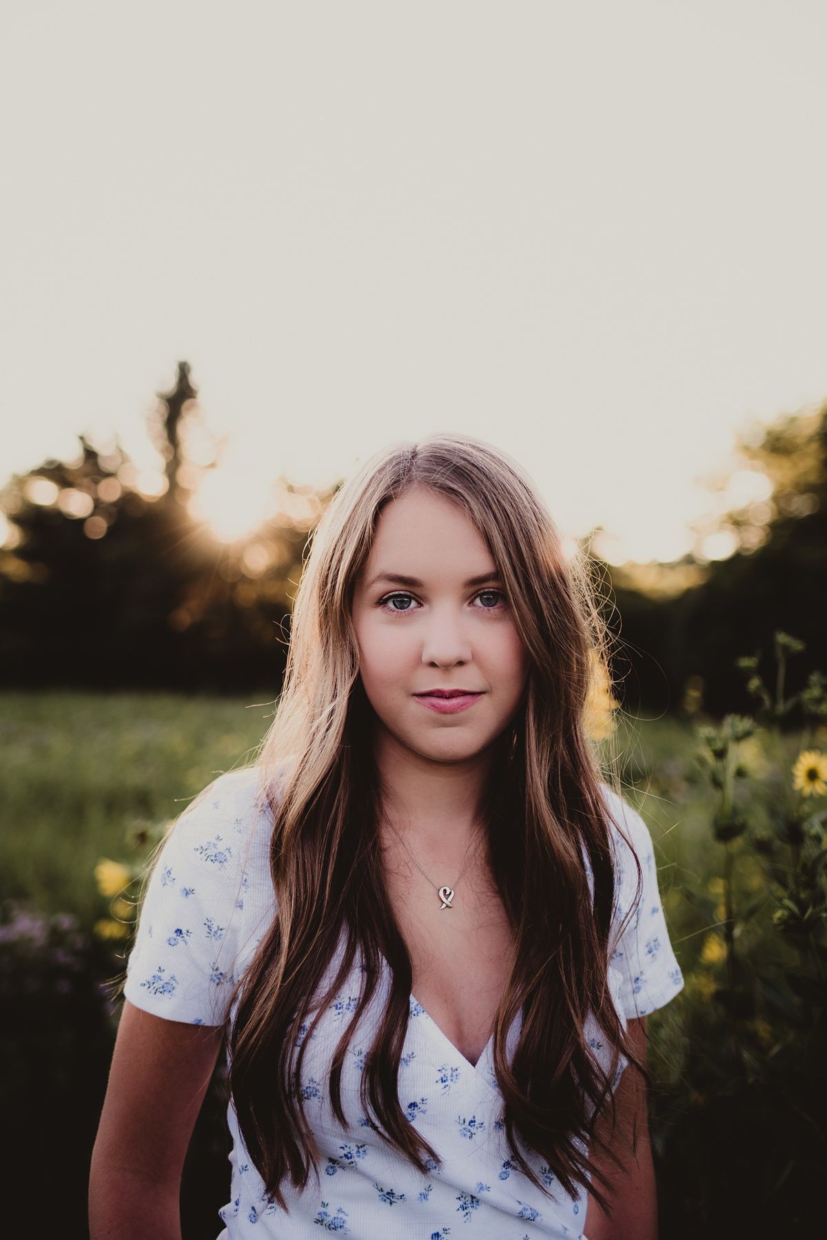 Backlit portrait at sunset in a field with golden light and yellow wildflowers.
