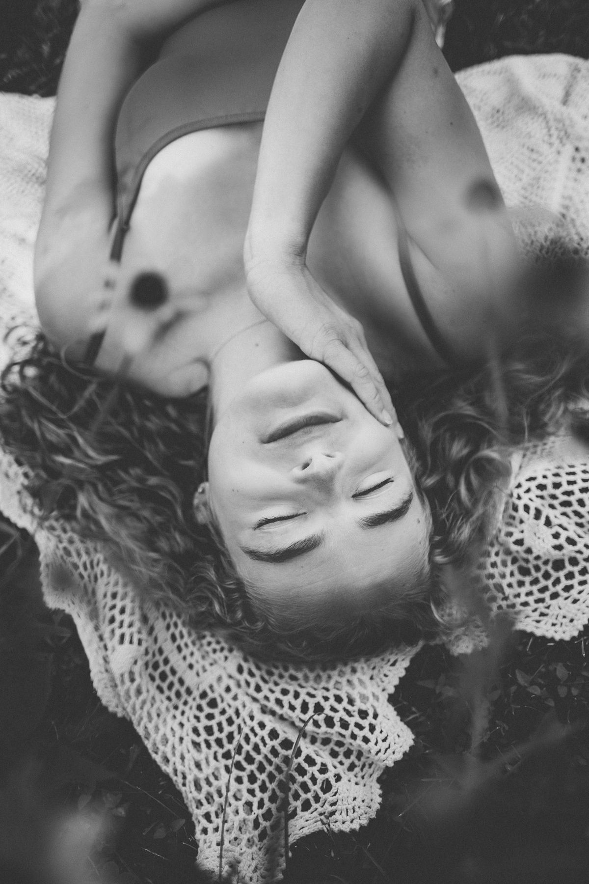 Black and white portrait on lace fabric with dramatic lighting and soft focus.