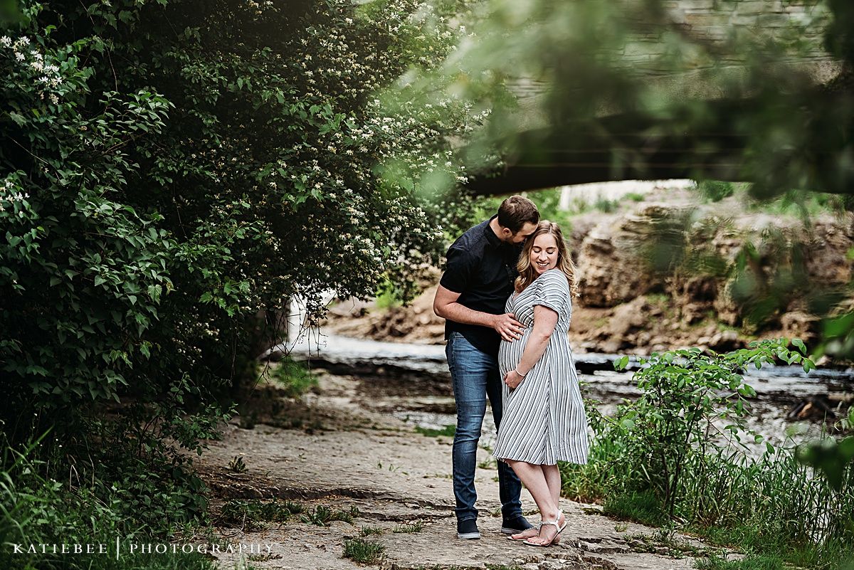 A tender maternity moment captured on a natural path by a stream.