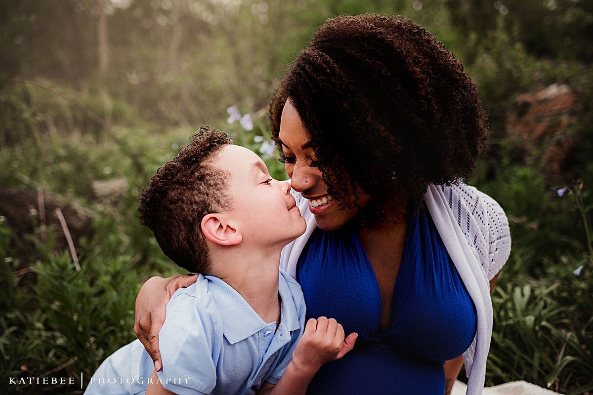 Intimate close-up portrait of mother and child touching noses in a loving gesture outdoors.