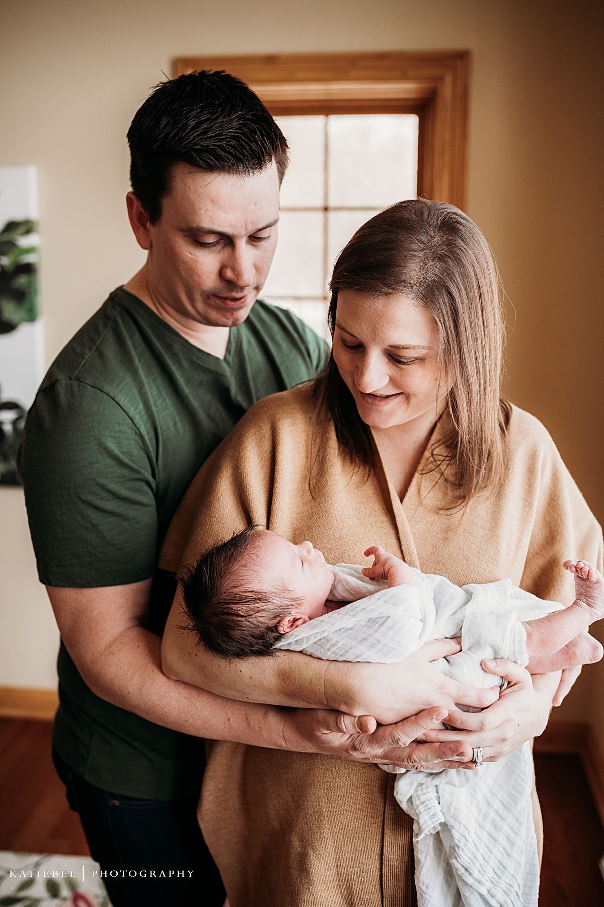 Intimate family portrait with newborn baby in sunlit room.