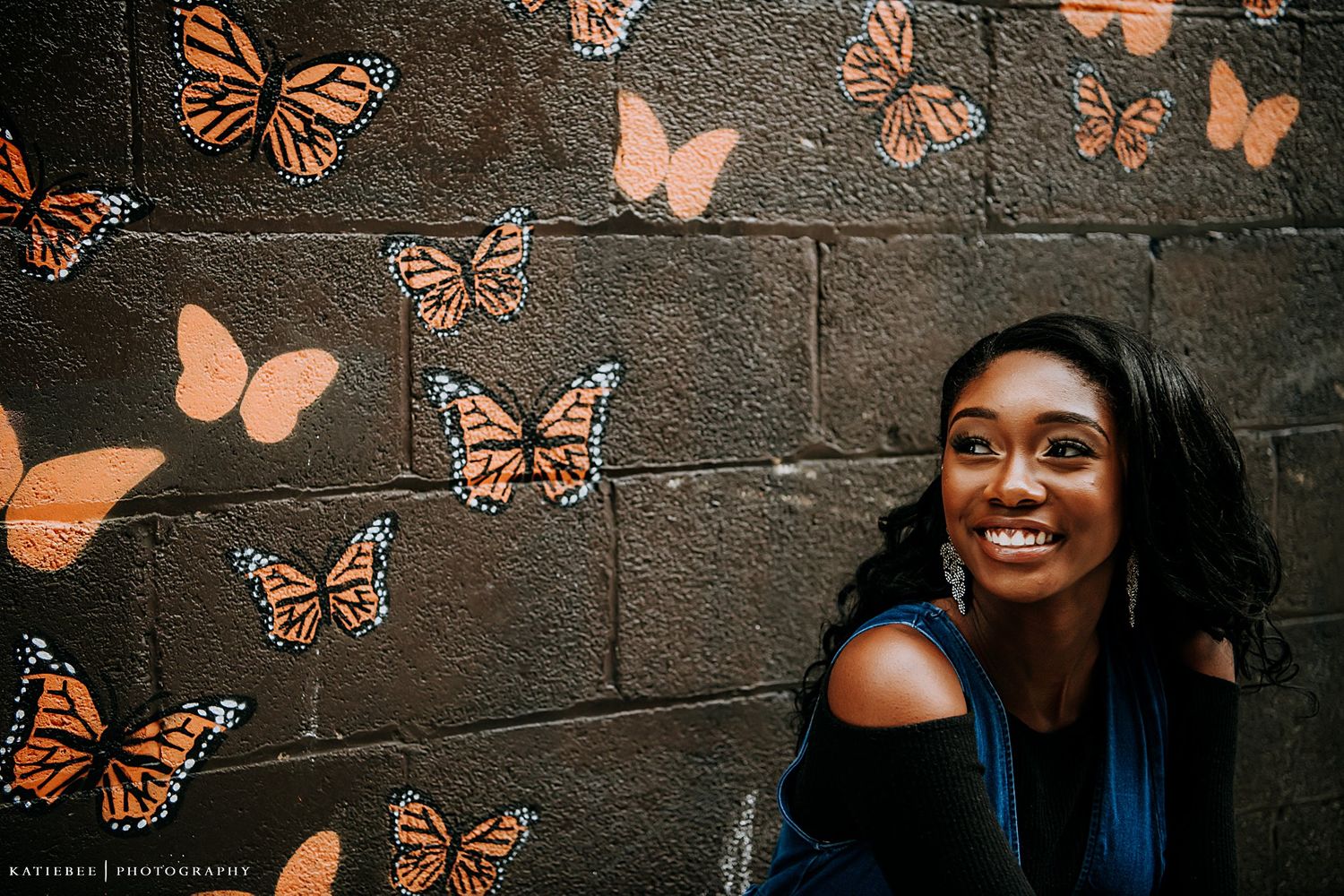 Joyful photo with orange butterfly wall art backdrop in an urban setting.
