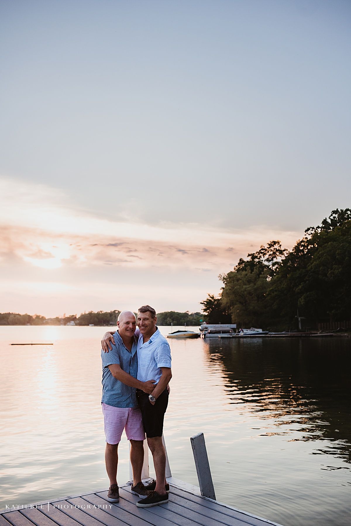 Two people embracing on a wooden dock during a golden sunset.