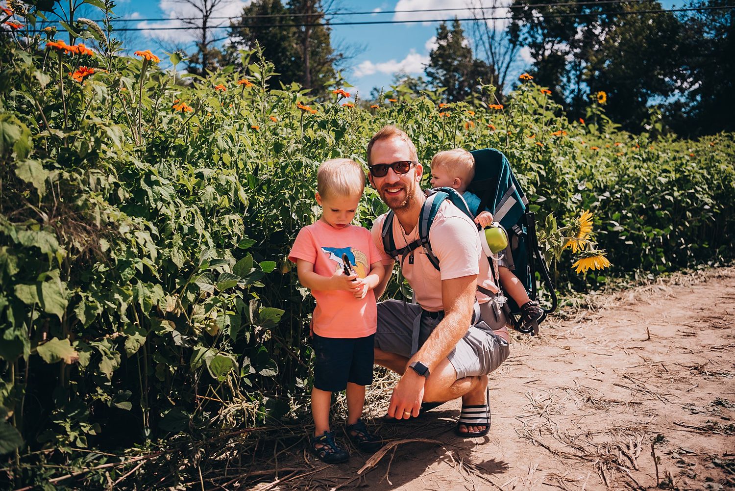 A family explores a flower garden trail on a sunny day.