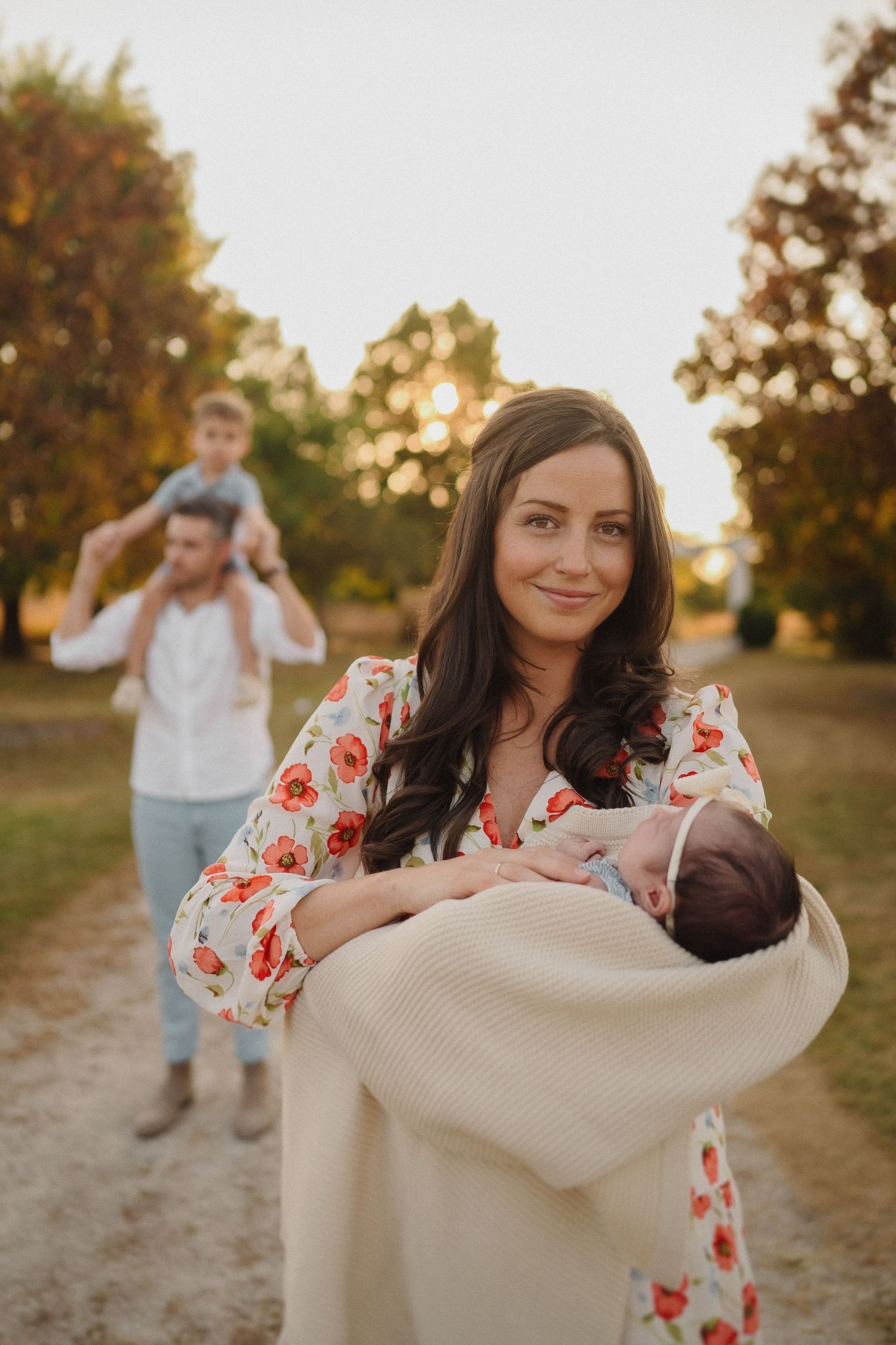Peaceful family moment captured on nature path during sunset with baby in arms.