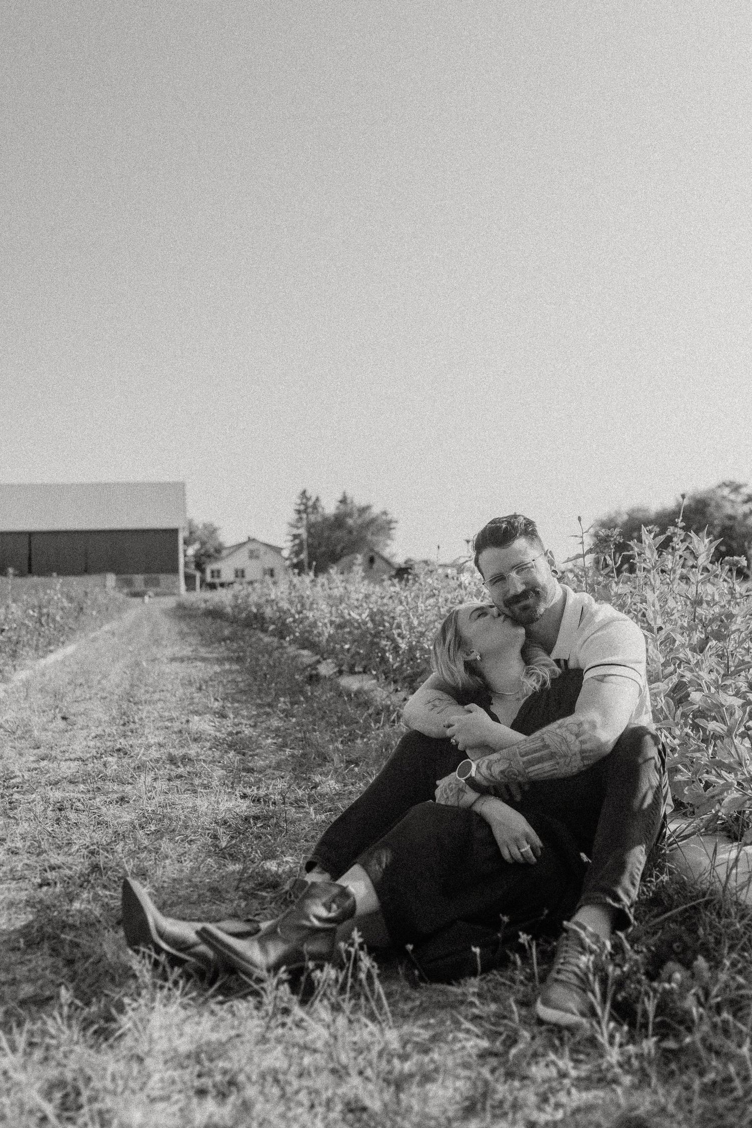 Black and white portrait of a couple sitting together in a countryside setting.