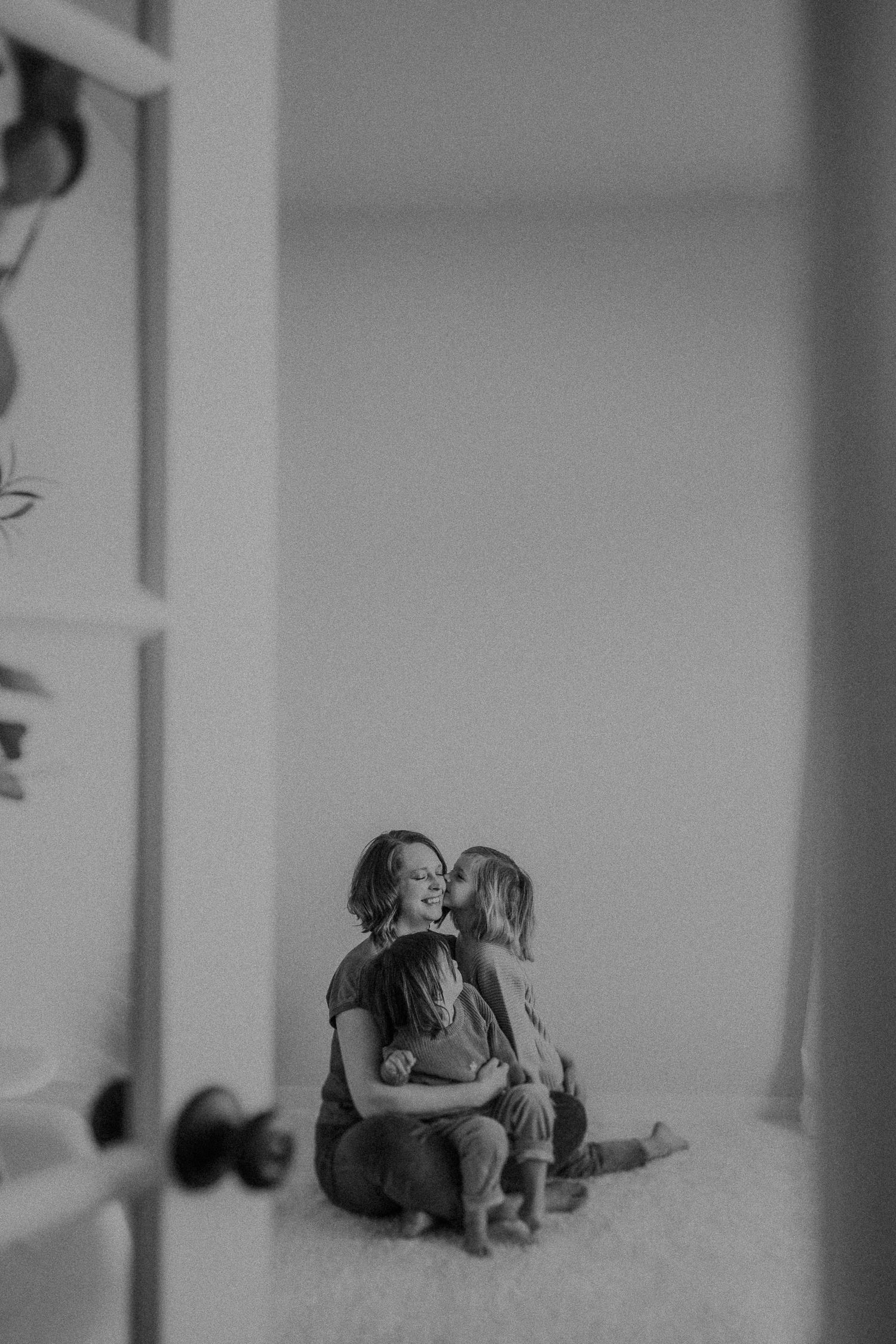 A tender moment between two people sitting by a door in moody black and white lighting.