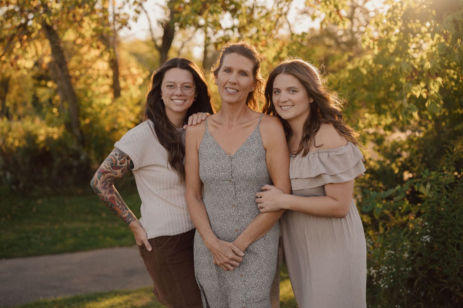 Group portrait in natural setting with warm sunset lighting and trees in background.