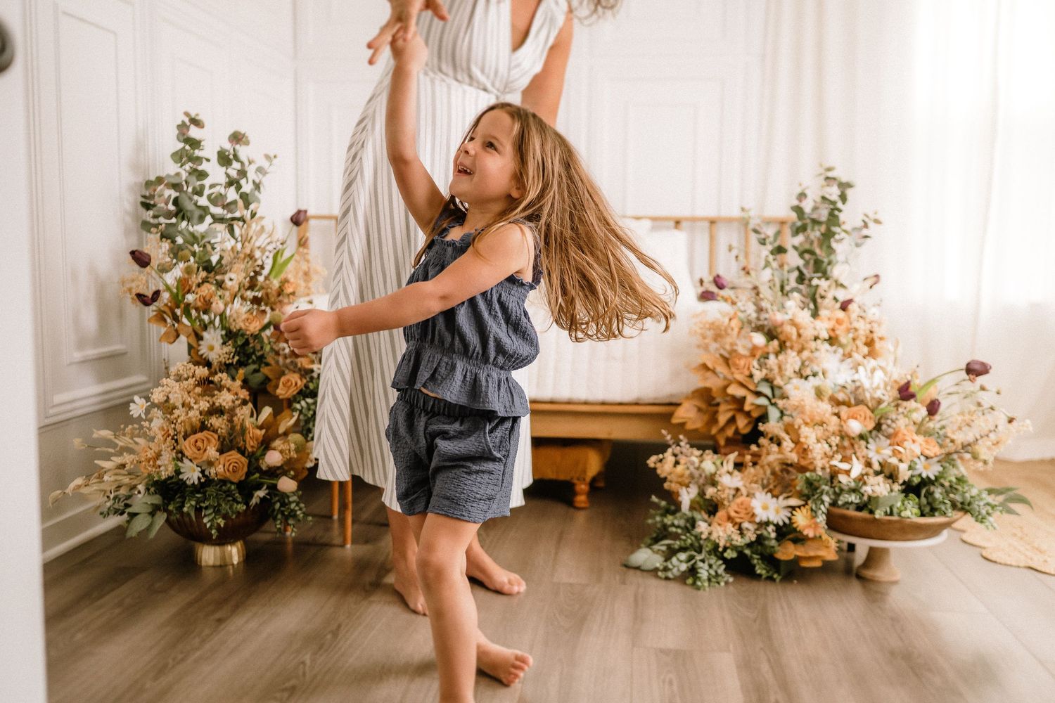 Dancing figure twirls joyfully in a bright room decorated with peach floral arrangements and greenery.
