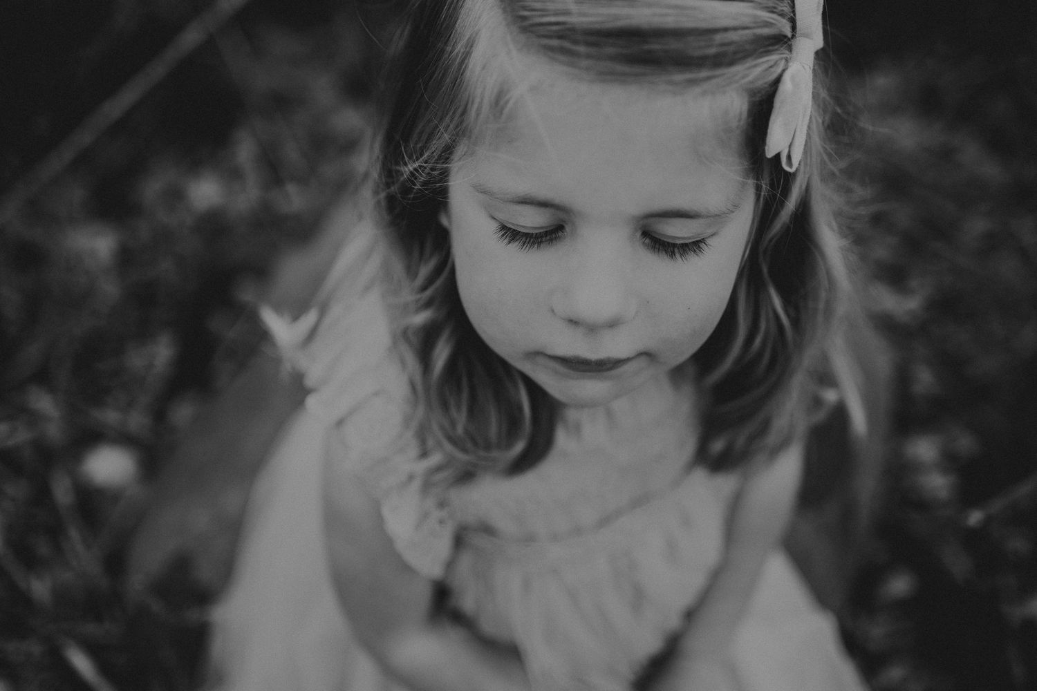 A black and white portrait showing a gentle downward gaze and soft expression.