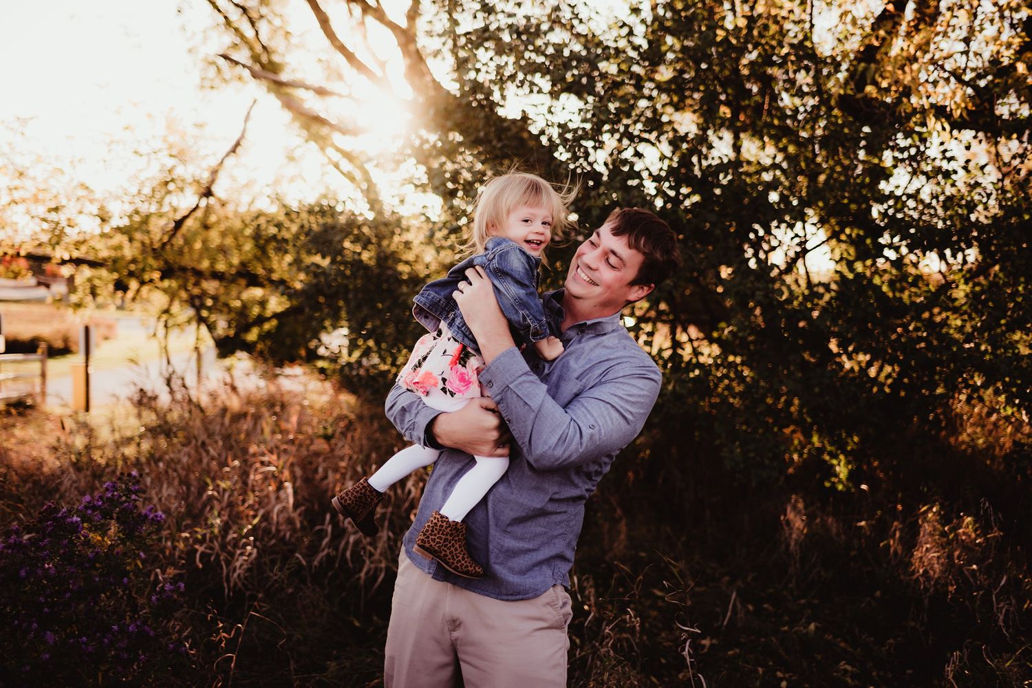 Two people share laughter and embrace during golden sunset in a backyard setting.