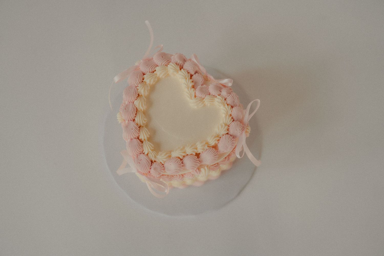 A delicate heart-shaped first birthday smash cake decorated with pink and white frosting.