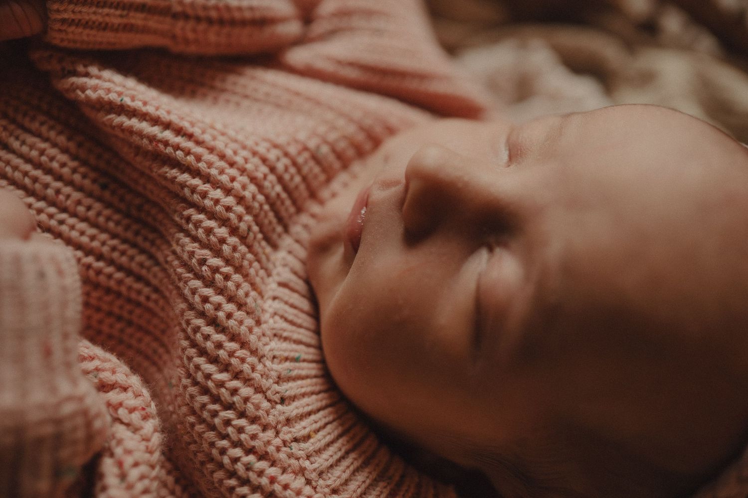 Close-up view of someone resting peacefully in a cozy knit sweater with warm lighting.