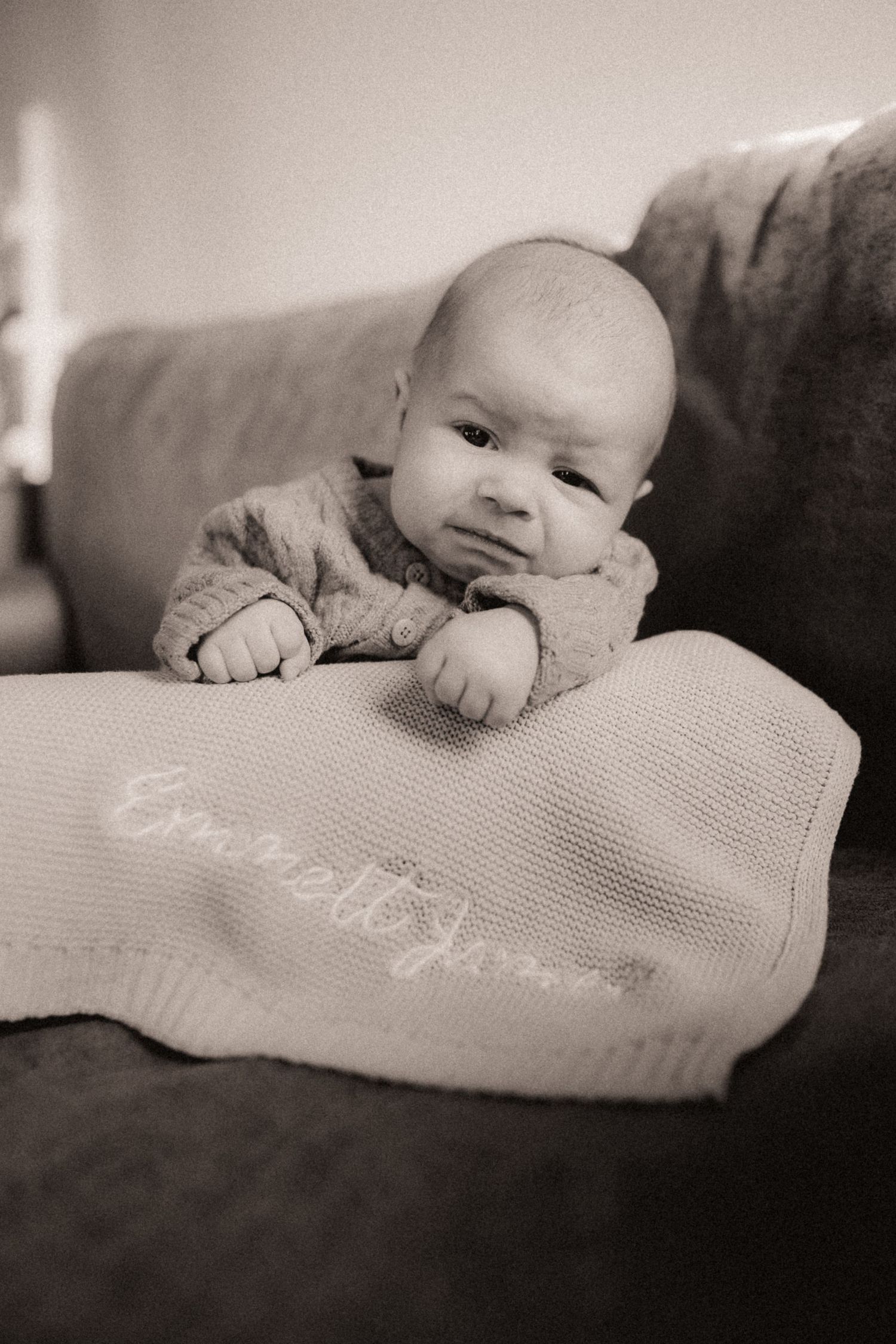 Black and white series of a baby lying on a textured blanket showing different angles.