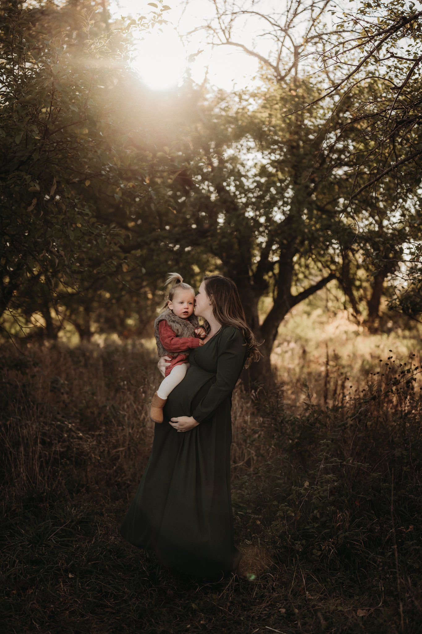 Silhouette of figures embracing against sunlit trees in a natural outdoor setting.