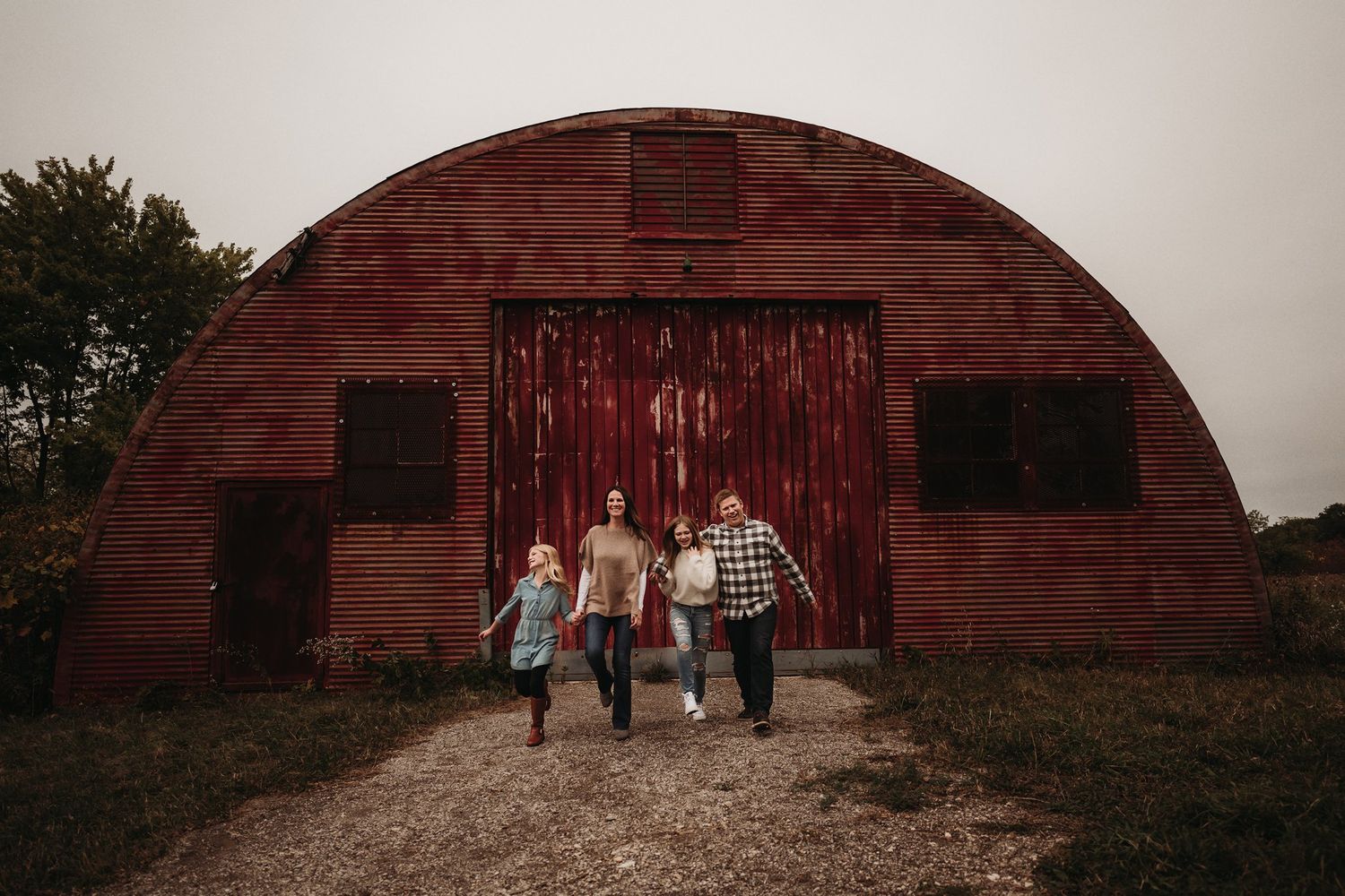 A group walks together in front of a large red barn structure with rustic doors.