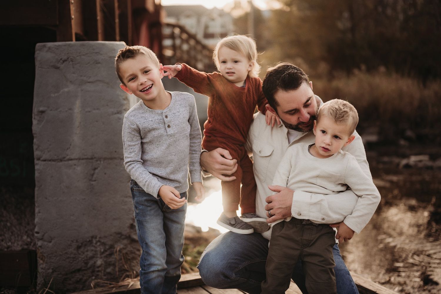 A candid outdoor family photo session with tender interactions against a golden sunset backdrop.