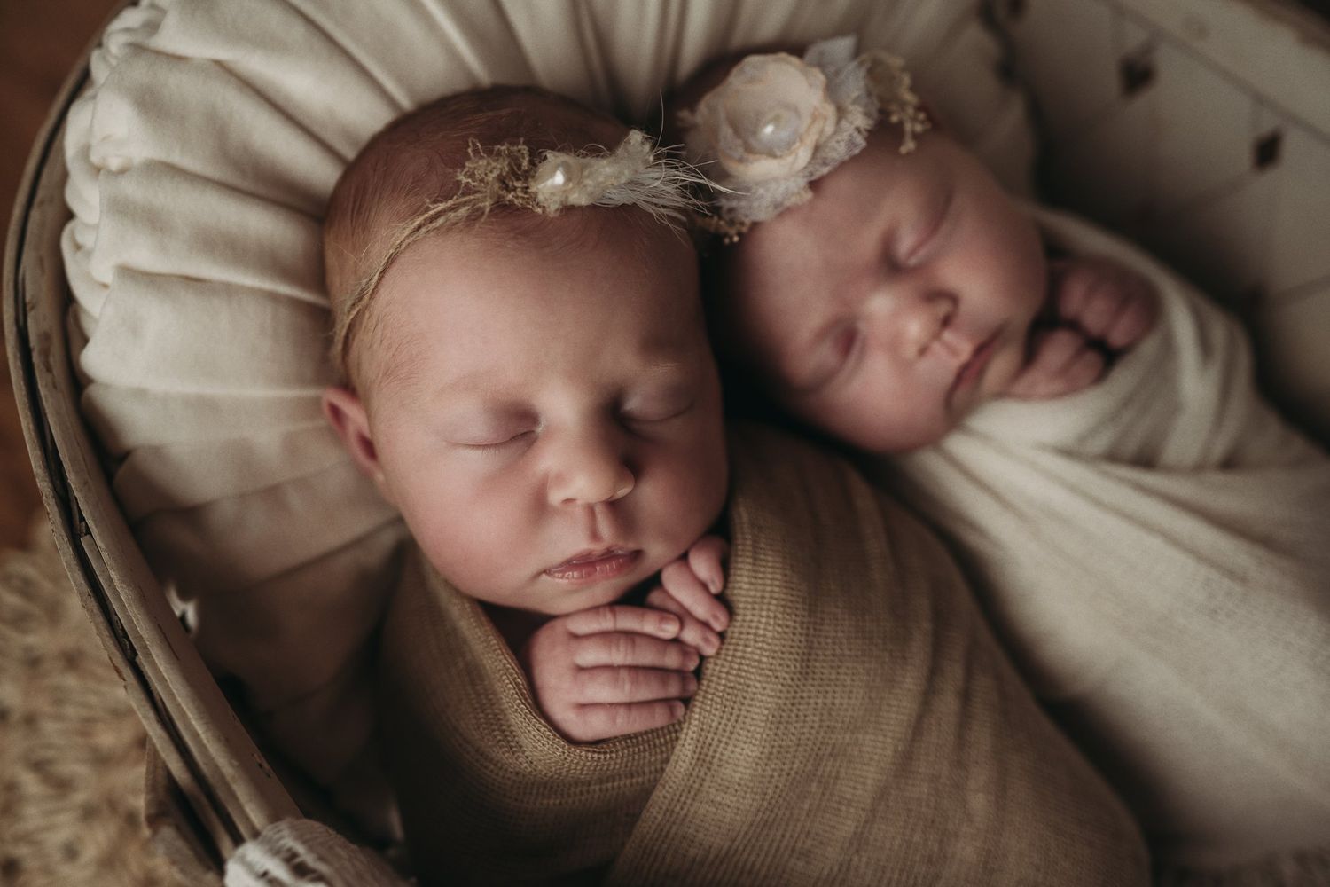 Close-up of twin babies sleeping peacefully side by side wearing delicate headbands.