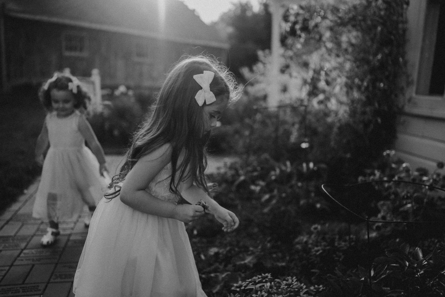 Black and white image of children playing in a garden with flowing dresses.