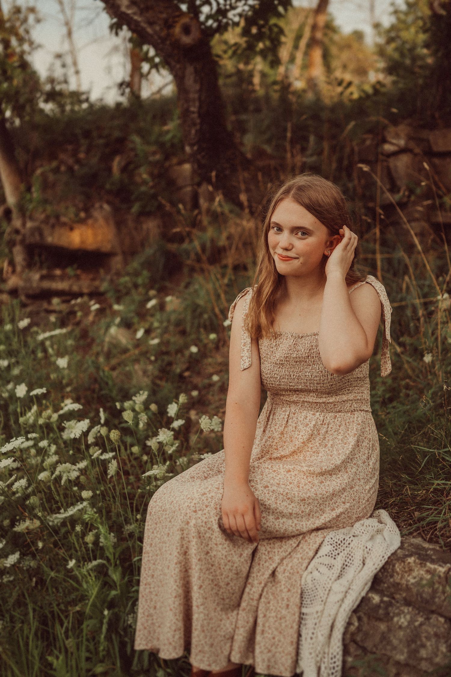 A gentle outdoor portrait featuring a beige sundress against a natural garden setting.