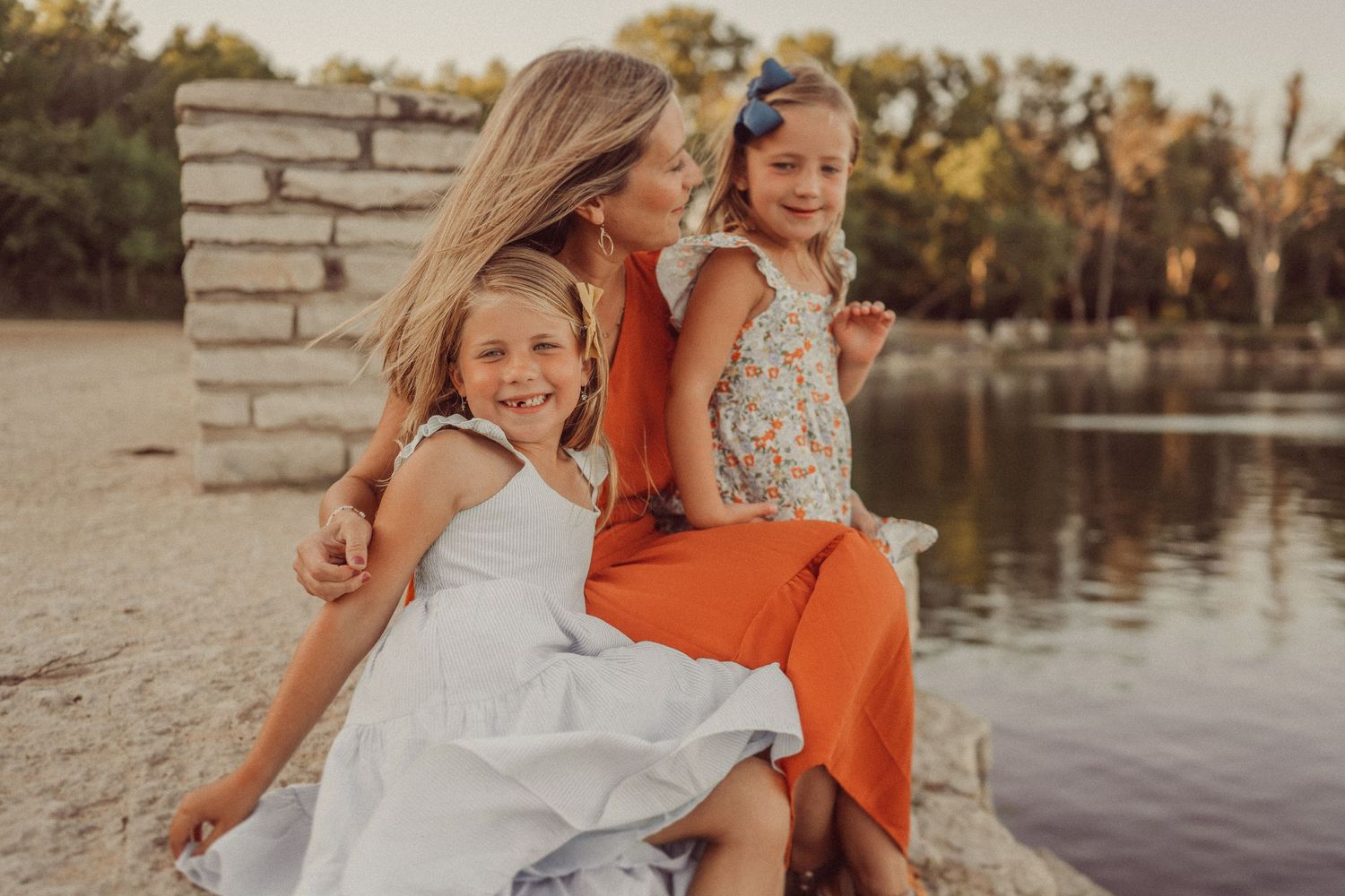 A warm sunset portrait by a lake with stone pillars and natural lighting creating a cozy family atmosphere.