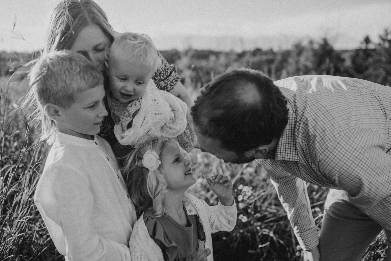Black and white portrait of intimate family moment in outdoor setting.