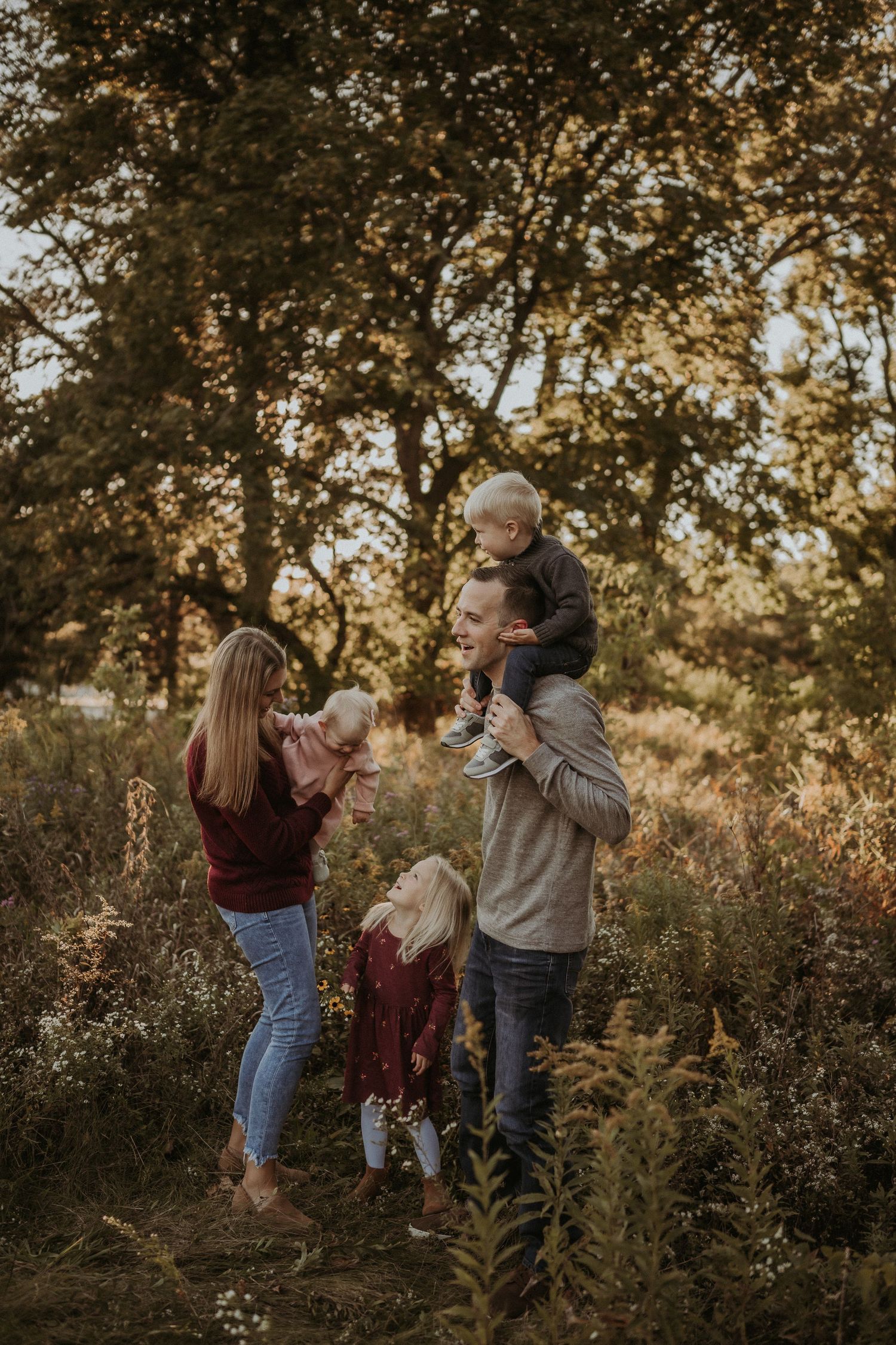 Family having fun together in a golden meadow during sunset with trees in the background.