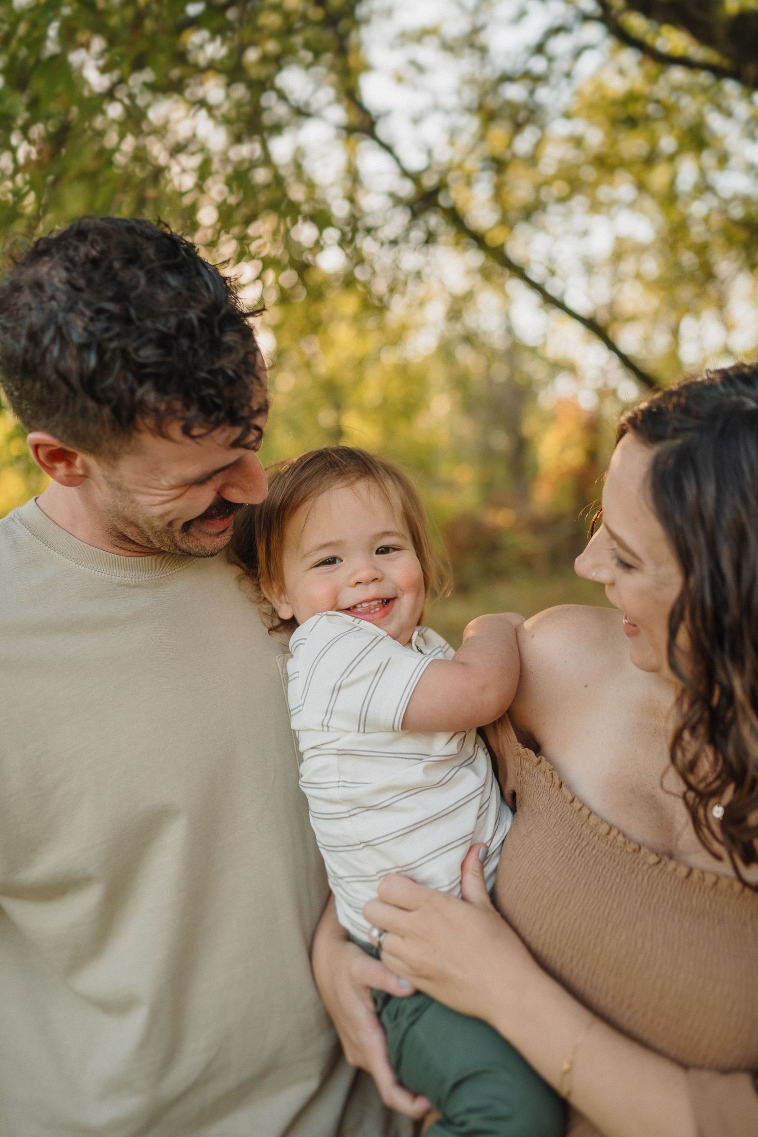 Candid family moment capturing natural smiles and laughter in warm autumn light.