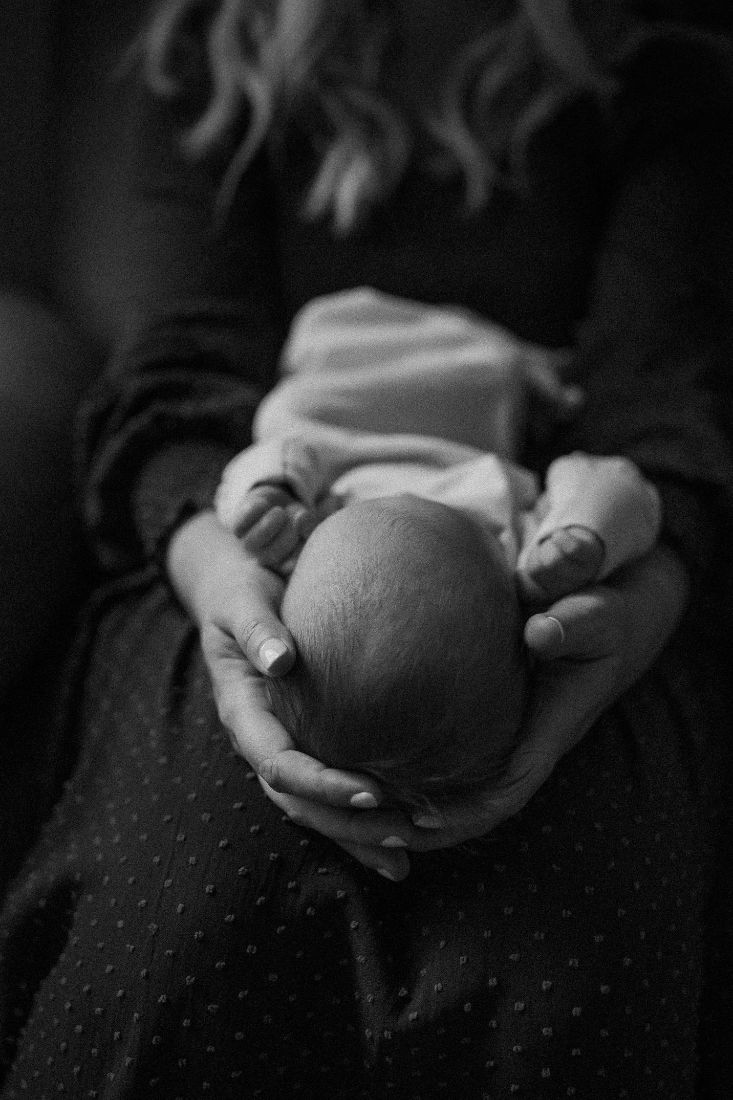 Black and white close-up photos showing gentle hands cradling a newborn.