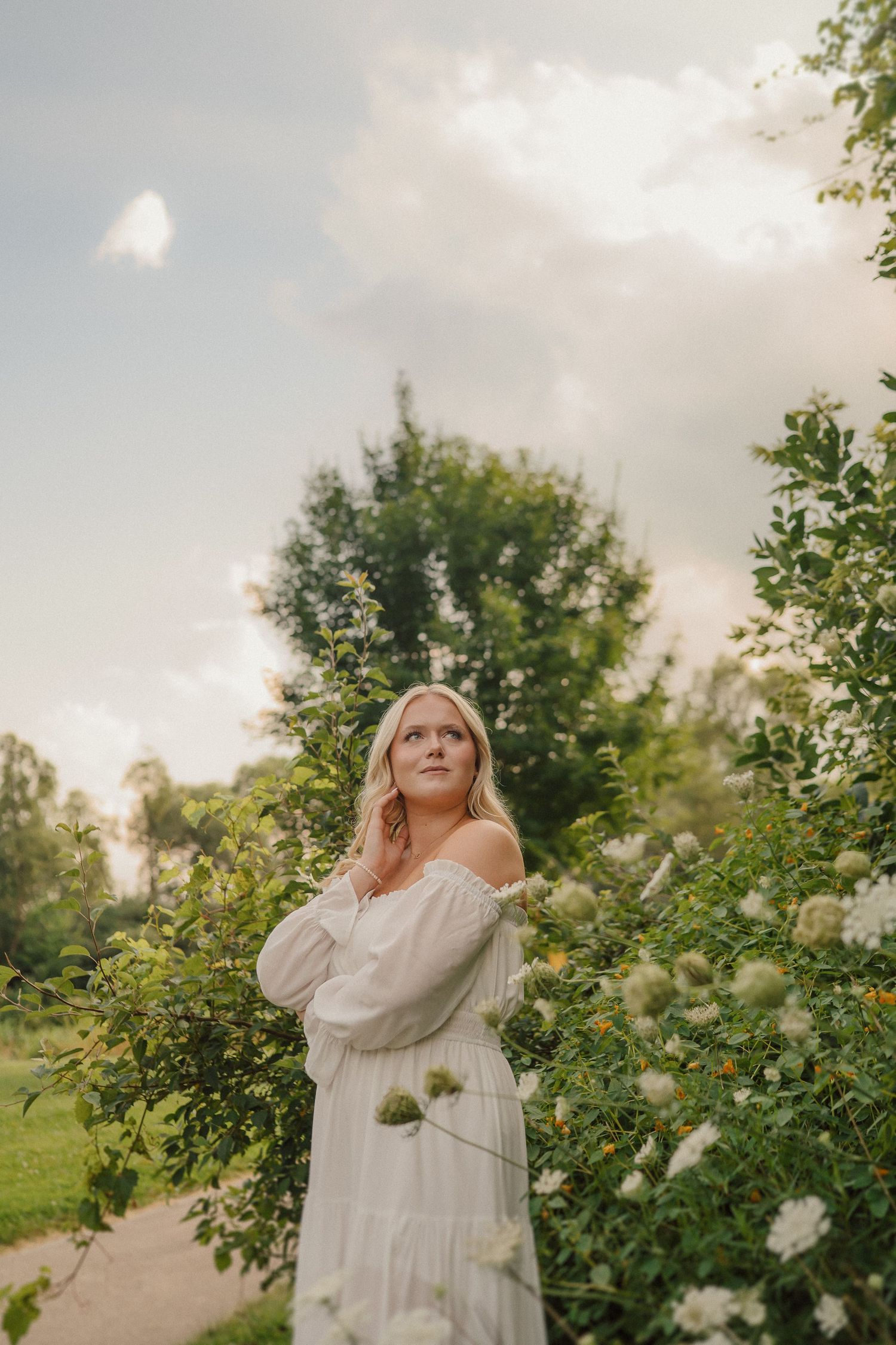 An ethereal scene in a garden with white roses and sunlit trees creates a dreamy summer atmosphere.
