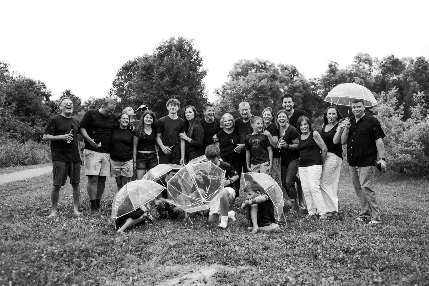 A large group poses lying down in grass for a creative panoramic photo spread across multiple frames.
