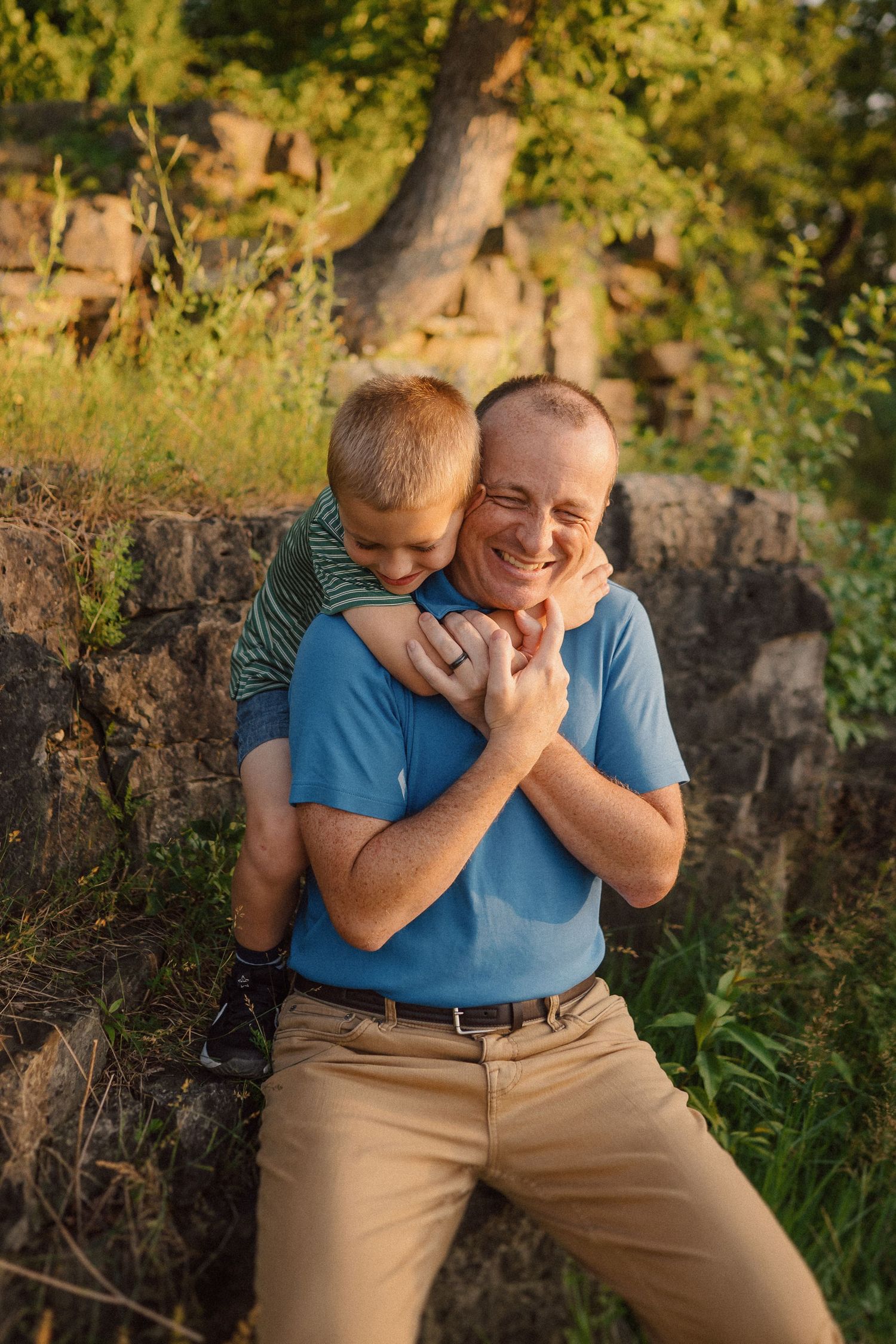 Playful moment captured in warm evening light against a backdrop of trees and stone wall.