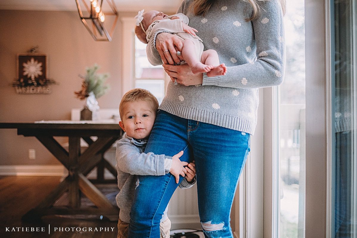Tender family moment captured by large windows in a warmly lit home interior.