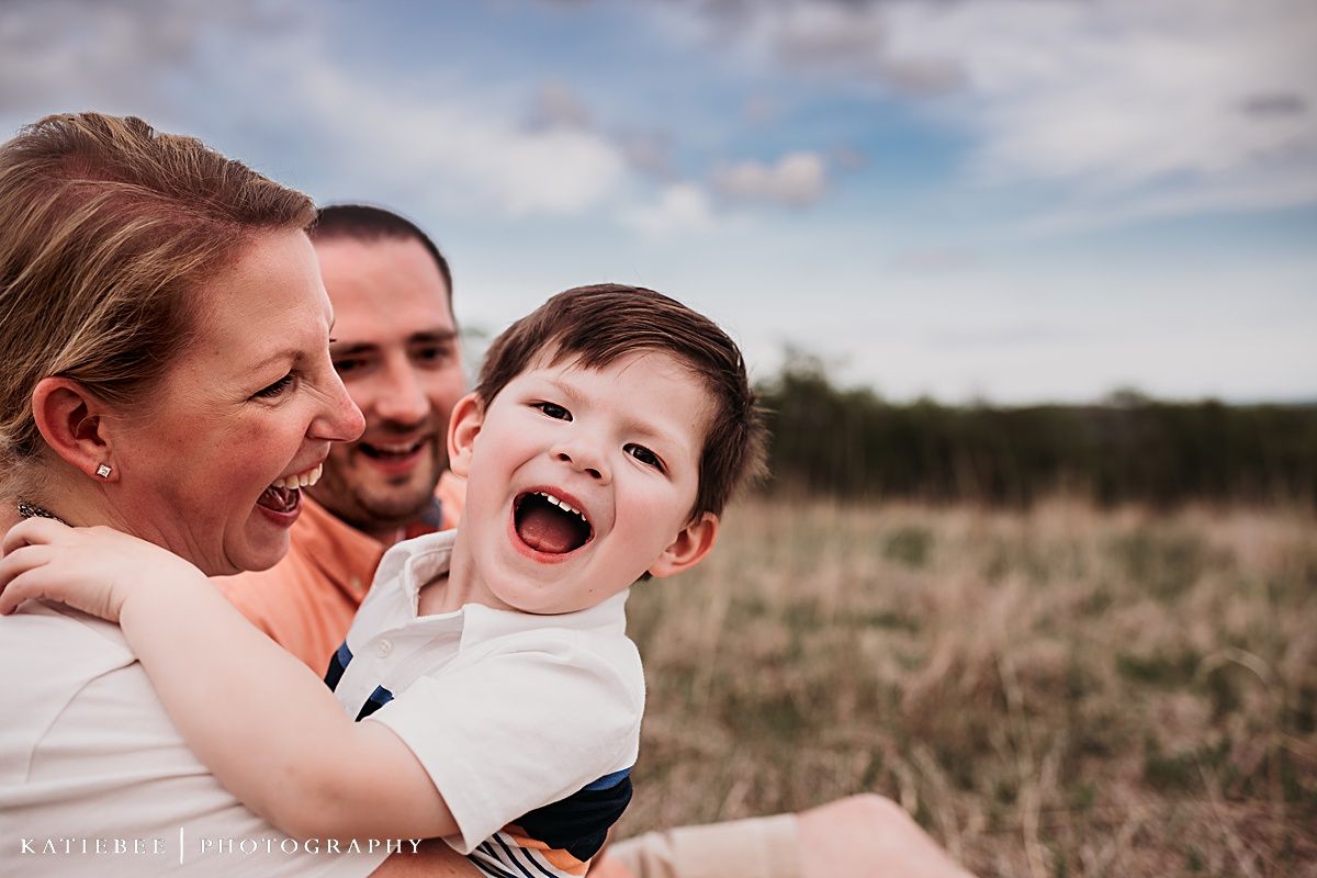Candid outdoor portrait of a joyful family laughing together in a field.