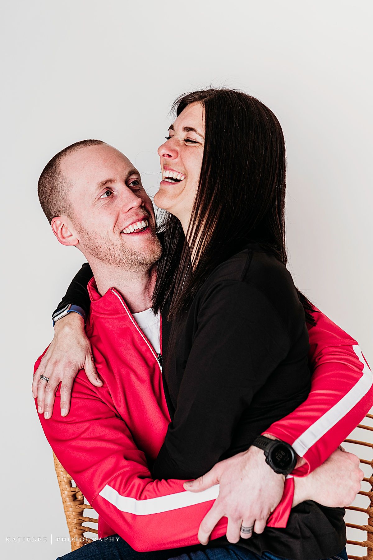 A couple sharing a joyful laughing moment together against a white background.