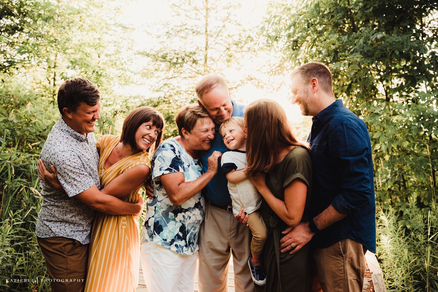 Candid family moment showing joyful laughter and embraces in a wooded setting.