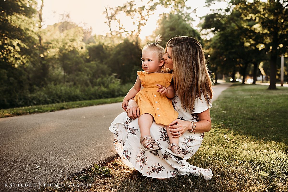 Sunset portrait of parent and child sitting together on grassy path.