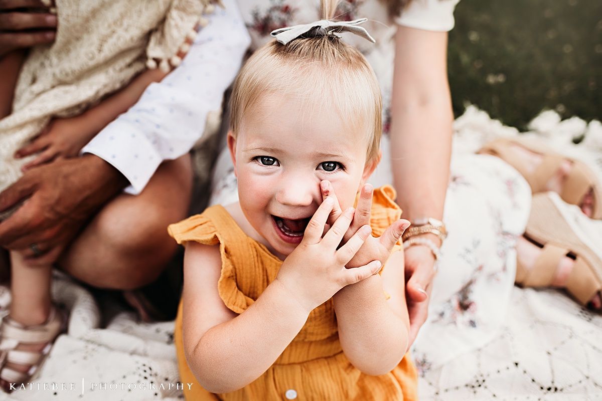 Close up of laughing child in orange dress during outdoor family photoshoot.